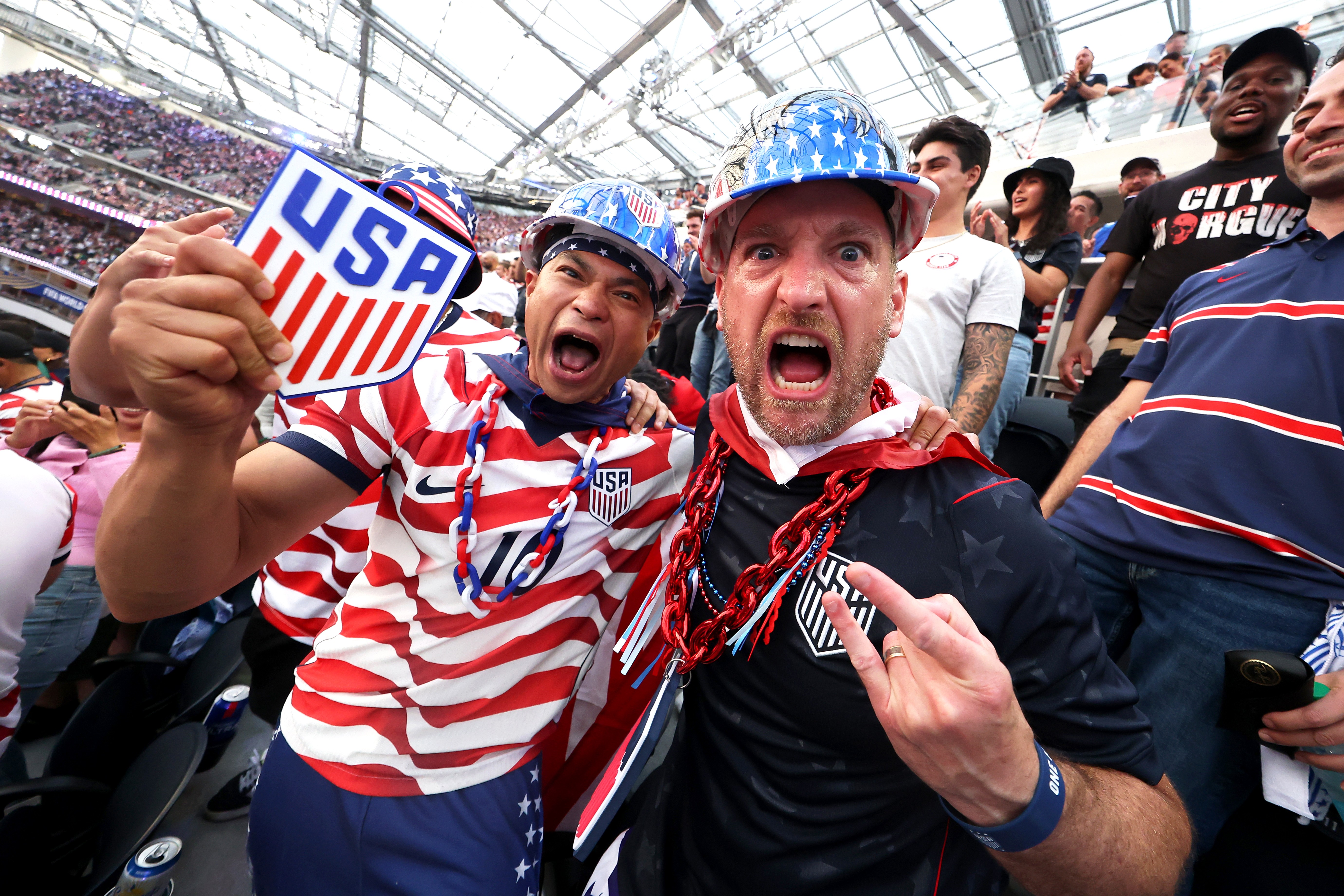 Fans of Team USA celebrate in a stadium after their team’s first goal.