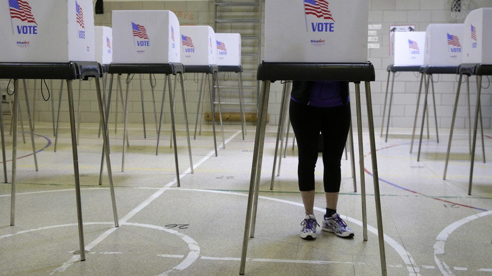 A woman votes in a voting booth at a school