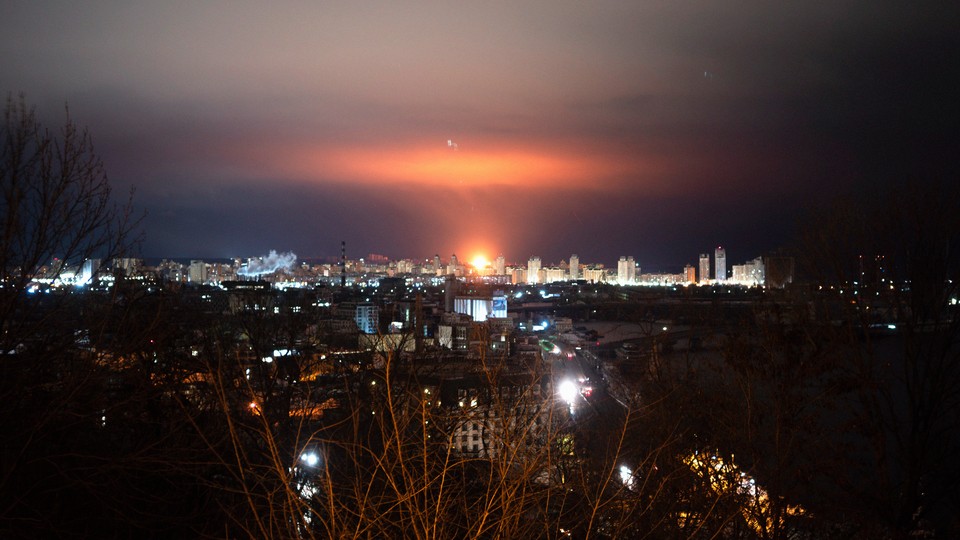 A photograph of Kyiv's skyline, in the dsitance and in the dark, lit up with ballistic missiles