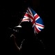 A silhouetted person holds up a Union Jack flag.