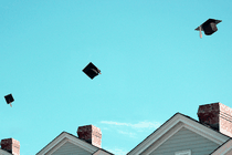 An illustration of graduation caps being thrown above houses.