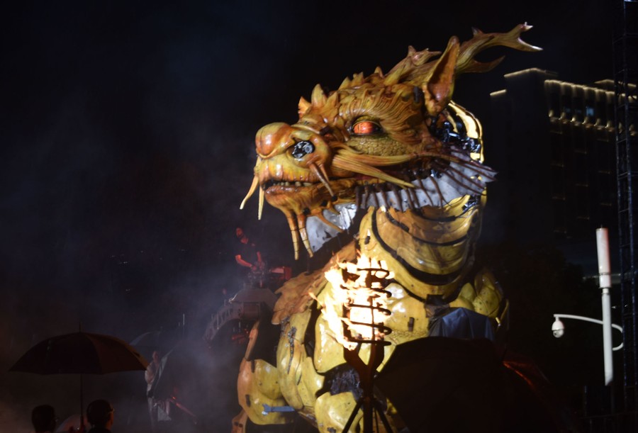 People look at a large mechanical dragon puppet.