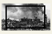 A smoke plume erupts from behind hollowed-out buildings on the Gaza Strip during Israeli bombardment