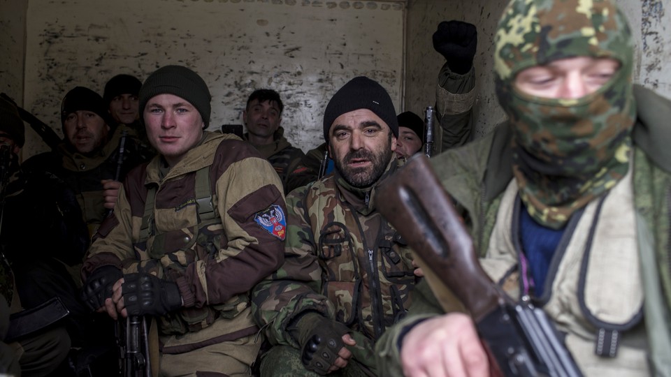 Pro-Russian rebels sit inside a truck, holding guns.