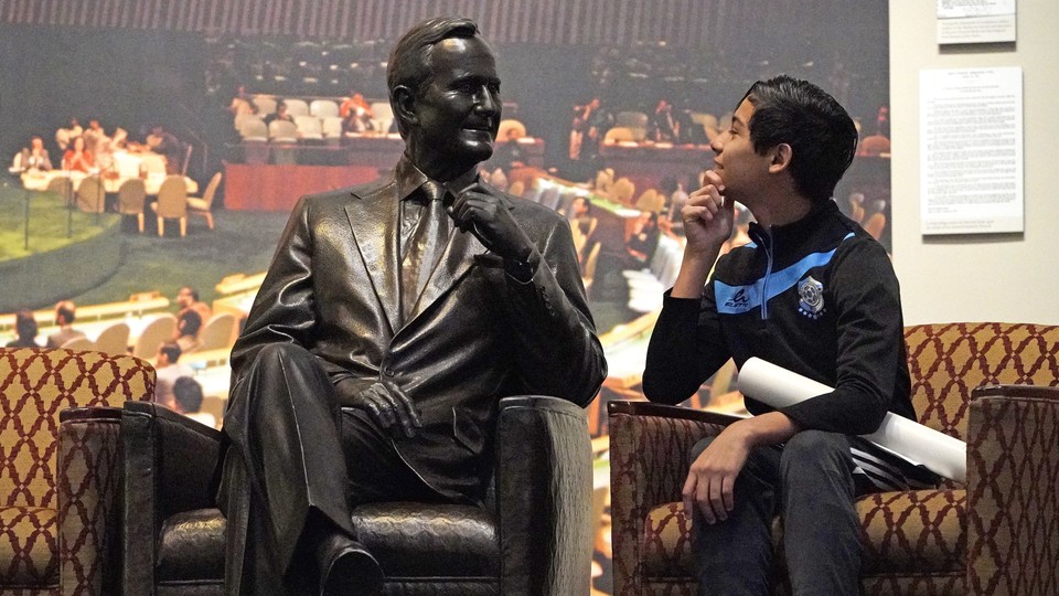 Andrew Lopez, 12, of Midland, Texas, next to a statue of George H. W. Bush inside the George H. W. Bush Presidential Library and Museum