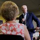 Joe Biden, wearing a blue suit and holding a microphone, speaks to a small crowd