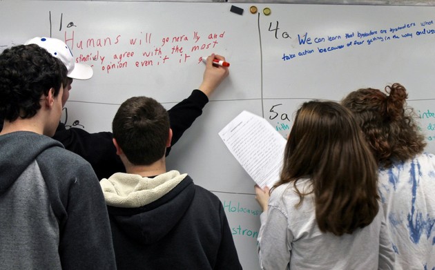 A group of students work at a whiteboard 