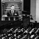 Black-and-white photograph of a crowd watching Xi Jinping speak at a podium