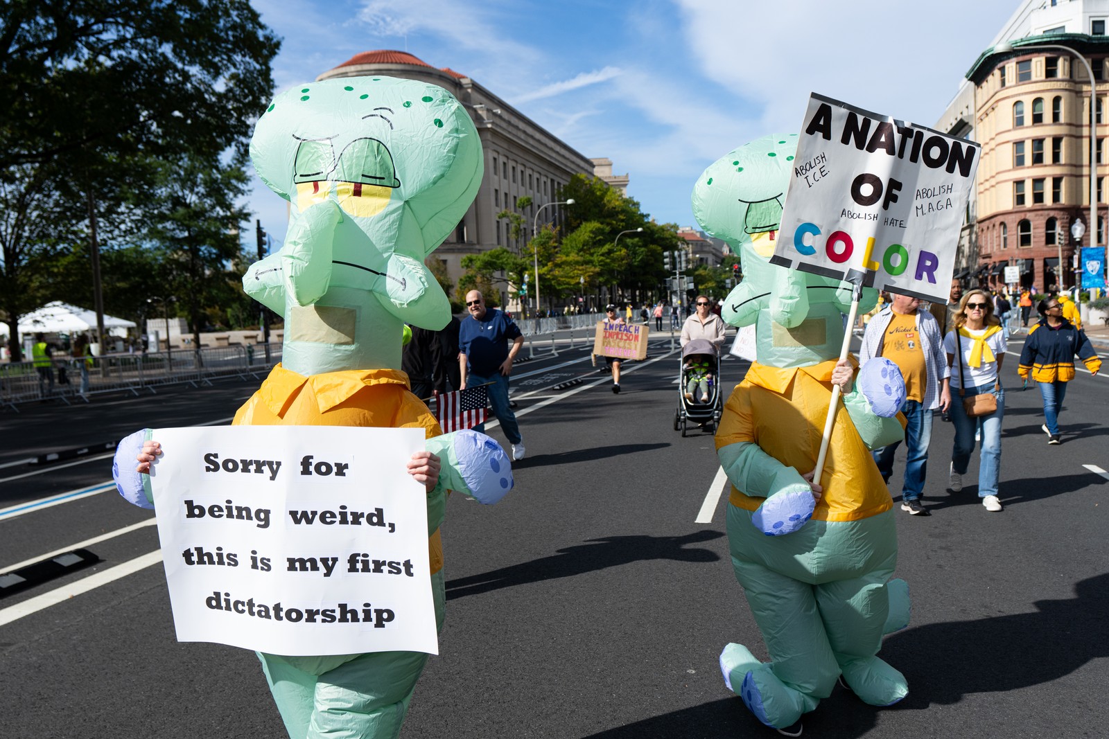 Two protesters wearing inflatable costumes of Squidward, a character from the SpongeBob SquarePants TV show, carry signs, including one that says