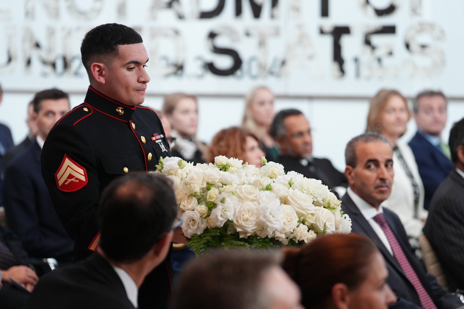 A member of the United States Marine Corps carries a memorial wreath during a ceremony.