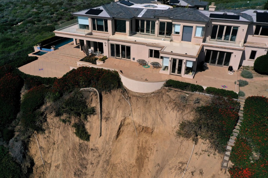 An eroded cliff face directly beneath a large house