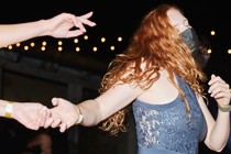 A woman dances at a party while wearing a mask