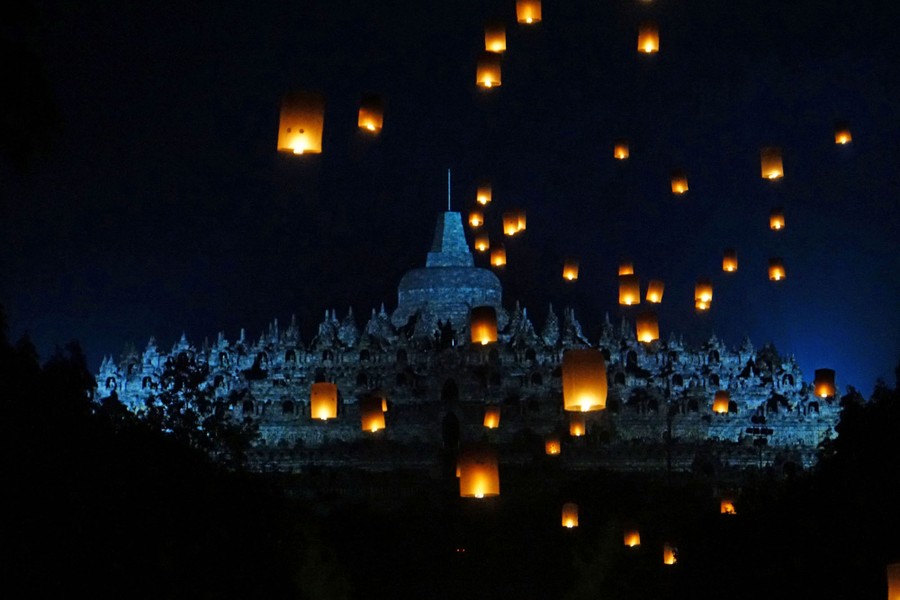 Paper lanterns fly near a temple.