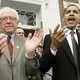 Barack Obama speaking at a Democratic rally in 2006 while Bernie Sanders claps beside him.
