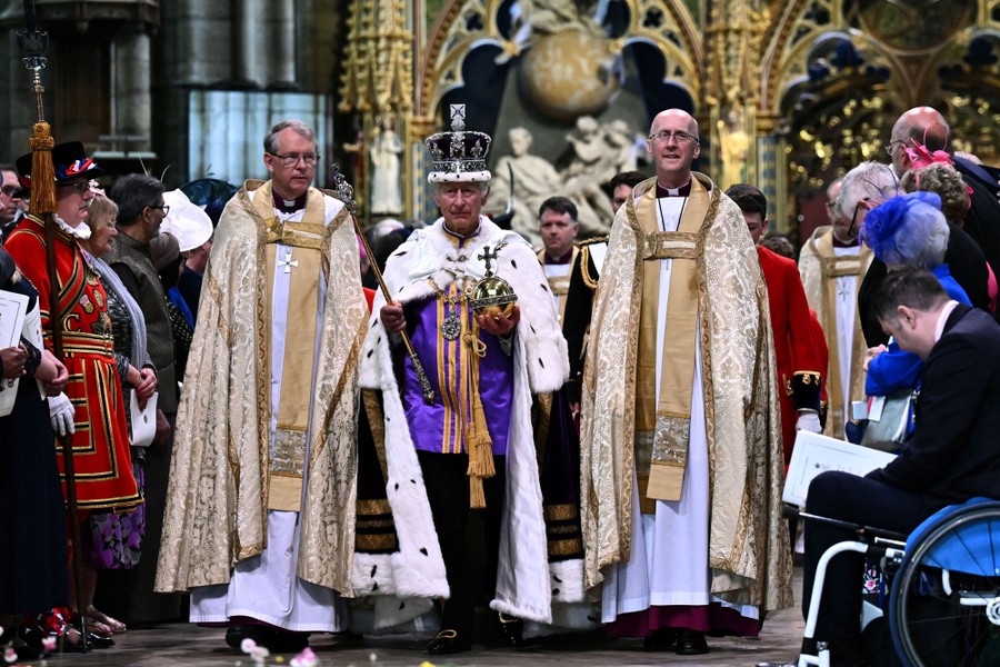 King Charles III, wearing  a crown and carrying an orb and scepter, leaves Westminster Abbey.
