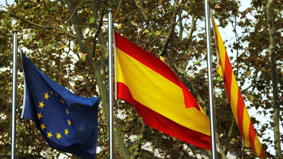 European Union, Spanish, and Catalan flags are seen.