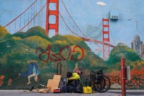 A homeless person in front of a mural in San Francisco