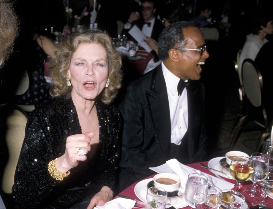 Lauren Bacall and Harry Belafonte share a table at an event.