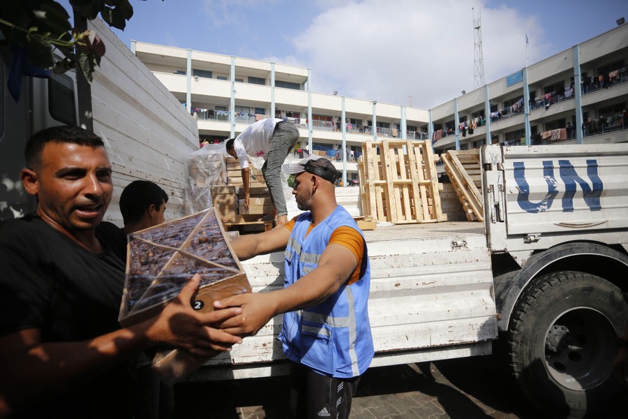 Several people lift crates of food from the back of a truck.