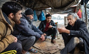 Bernard-Henri Levy in his latest documentary, speaking to three men in a large makeshift tent