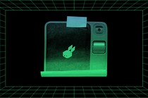 Illustration of an image of the Rabbit R1 printed on a piece of paper and stuck with tape onto a background