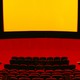 View of movie-theater seats and screen, in black, red, and yellow