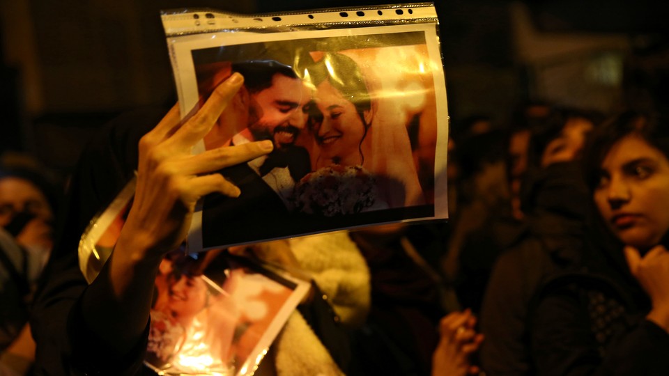 a woman holds a wedding picture depicting two victims of the crash of Ukraine International Airlines Flight 752.
