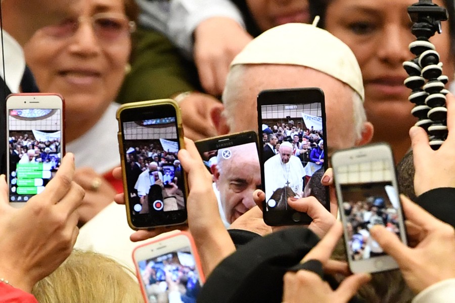 Half a dozen phones are held up, taking videos and photos of Pope Francis.
