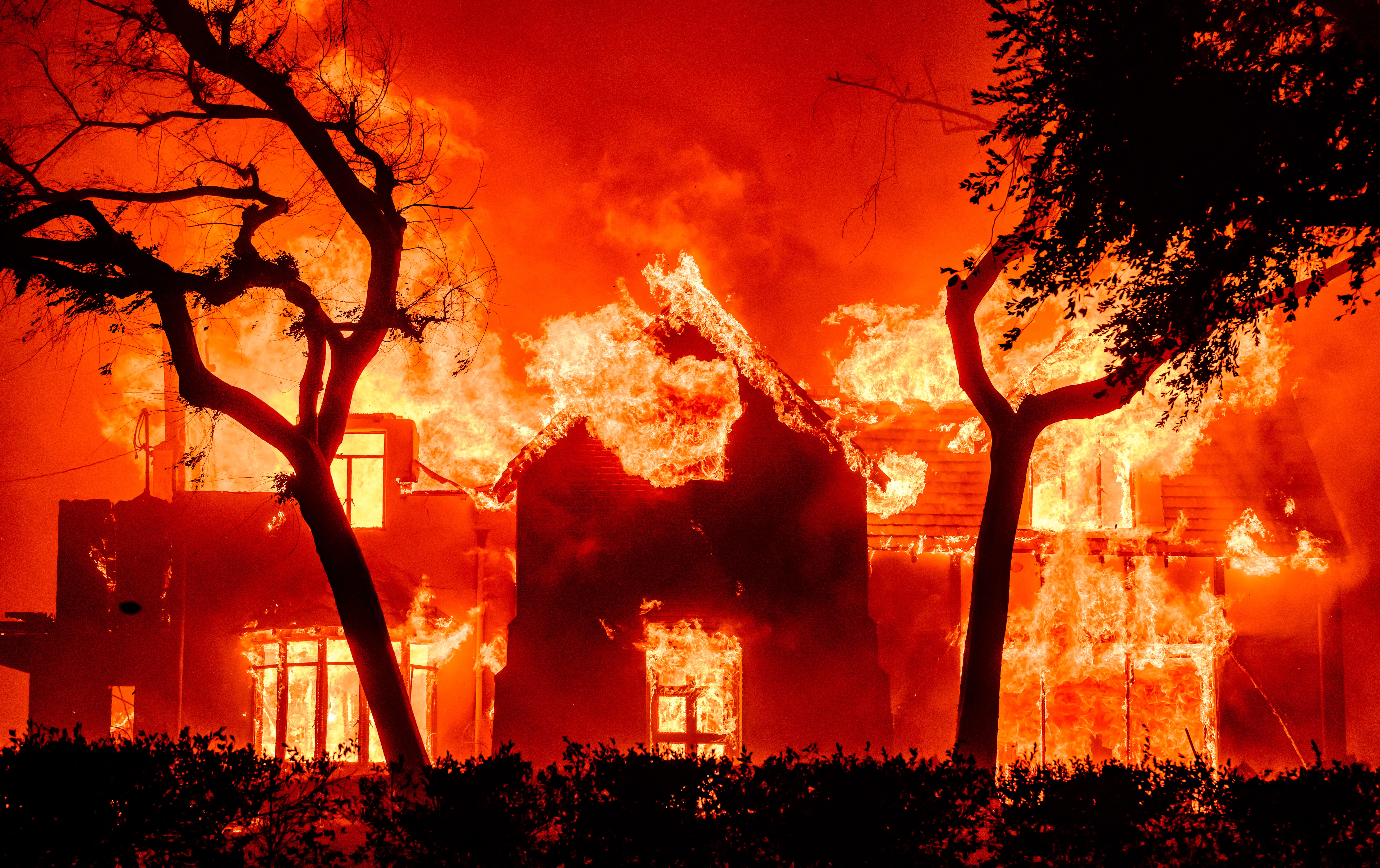 A home is engulfed in flames during a wildfire.