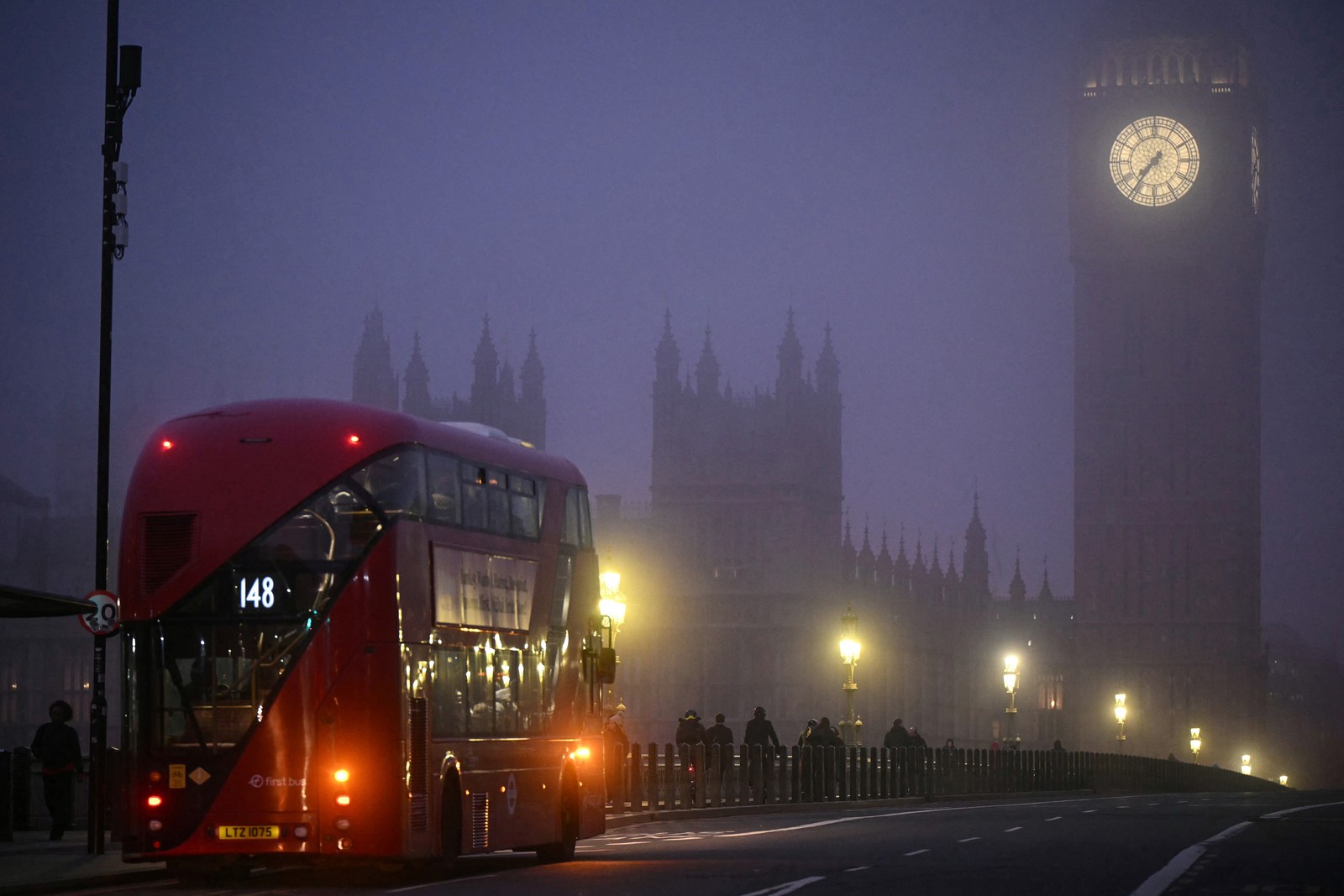 A double-decker bus crosses Westminster Bridge as fog covers the streets of London.