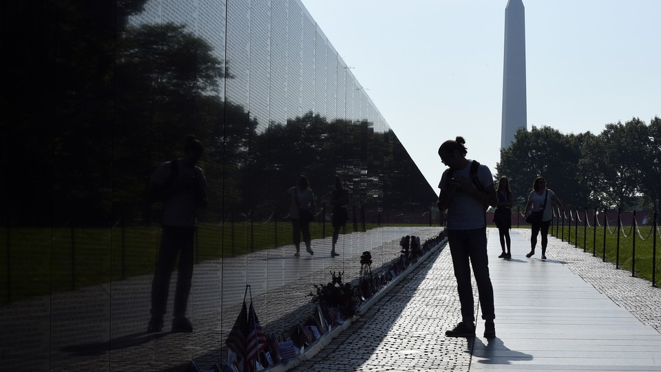 A photograph of a silhouette of a person observing the Vietnam Veteran's Memorial in Washington, D.C.
