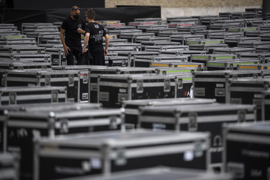 Two people talk among dozens of large wheeled travel cases.