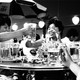 a black-and-white image of Asian women, seated around a table, toasting each other with mugs of beer