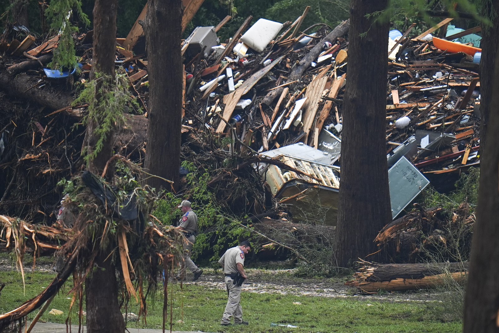 Several officials search near large piles of flood debris