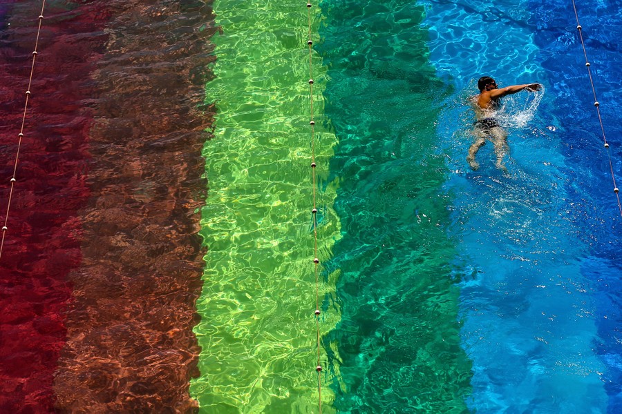 A person swims in a pool with rainbow stripes on the bottom.