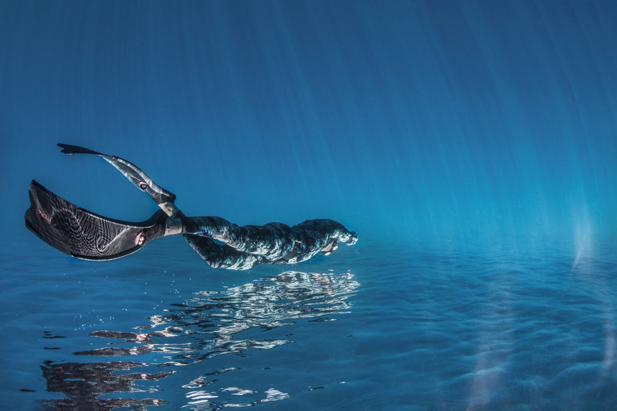 Una vista invertida de una persona nadando cerca de la superficie del océano.