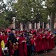 Doves fly over the heads of graduates dressed in deep red caps and gowns.