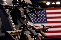 A photograph of two assault rifles on a store shelf, with the American flag visible behind them.