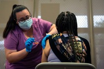 a health worker administers a vaccine to a person sitting in a chair