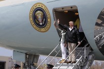 Donald and Melania Trump wave from the stairs of a plane.