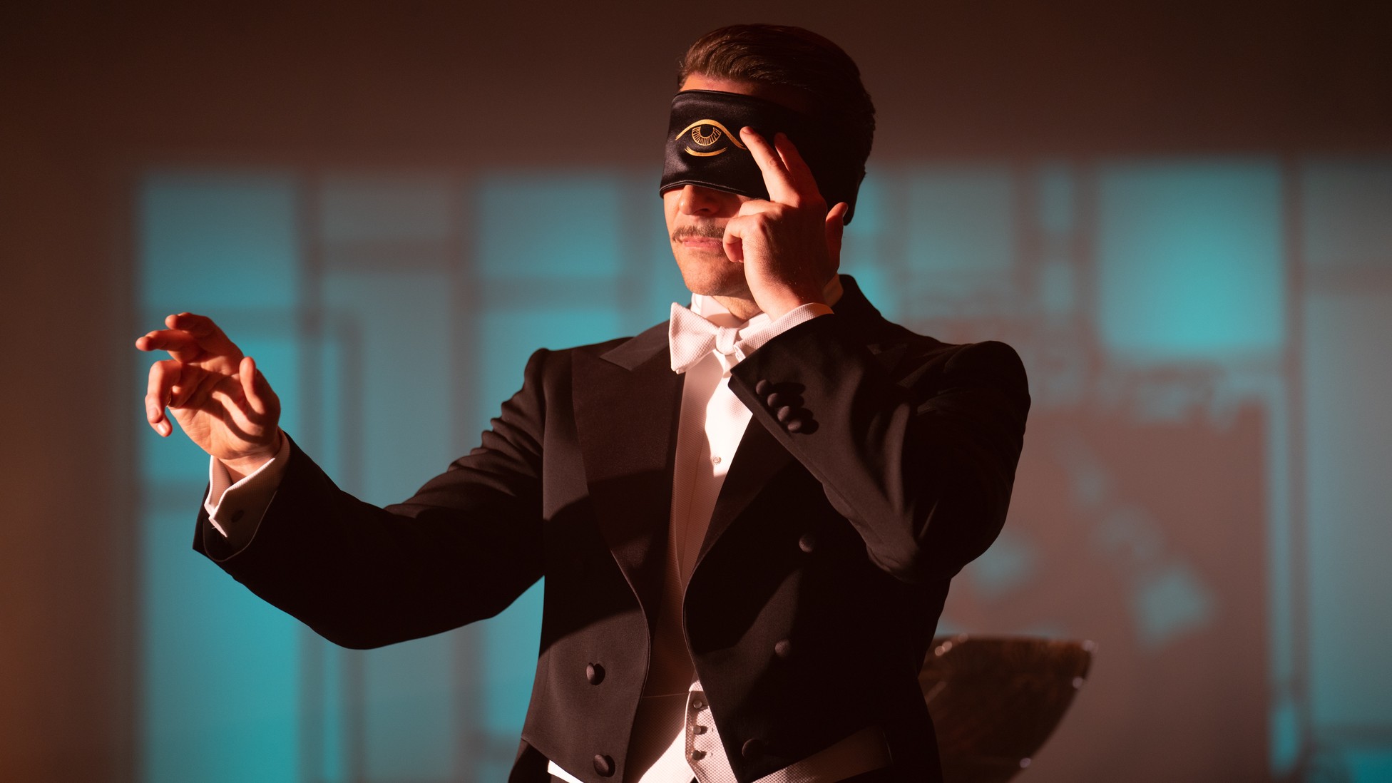 Bradley Cooper in a tuxedo with an eye mask over his face