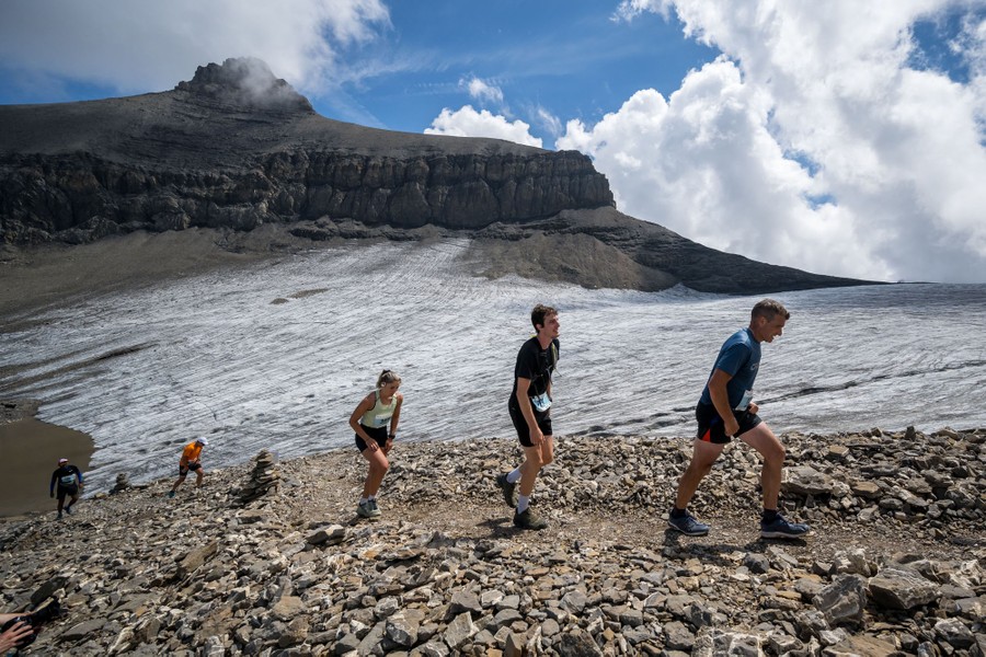 A half-dozen runners climb a trail alongside a glacier high in the mountains.