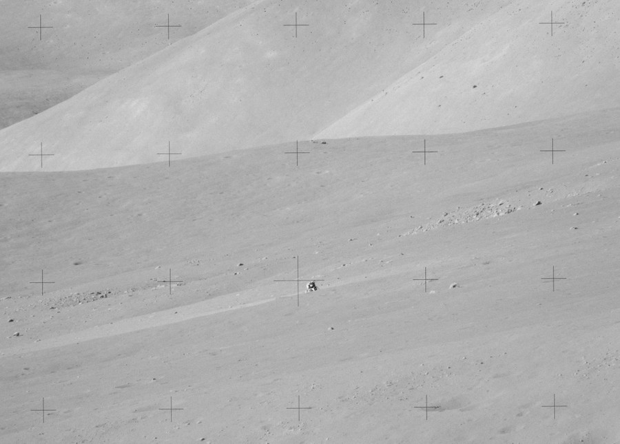 A distant view of a lunar lander on a broad and empty moonscape