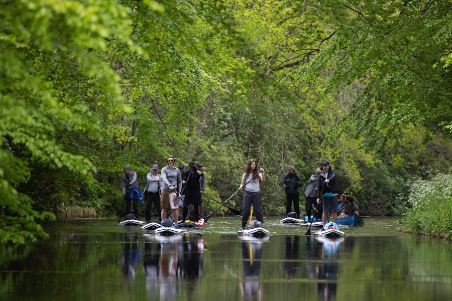 Eleven people paddle on a canal.