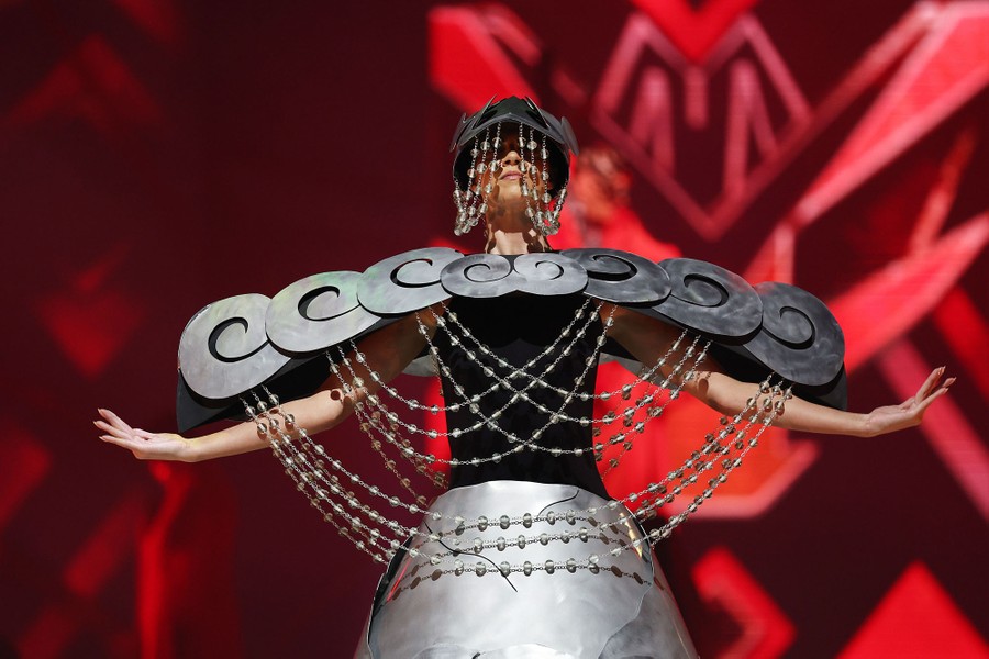 A model poses, wearing a broad-shouldered costume made partly of metal sheeting.