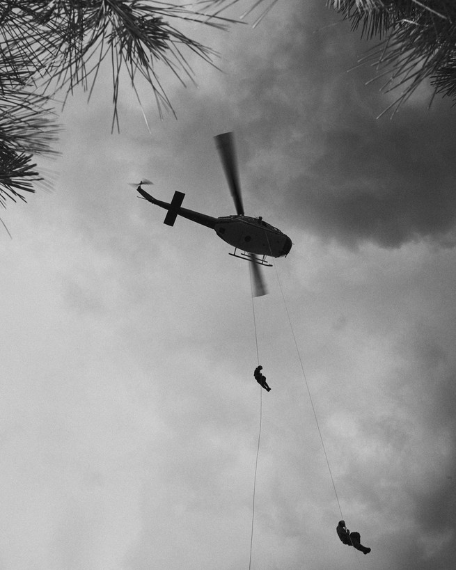 Smoke jumpers descending from a helicopter, seen from the ground 
