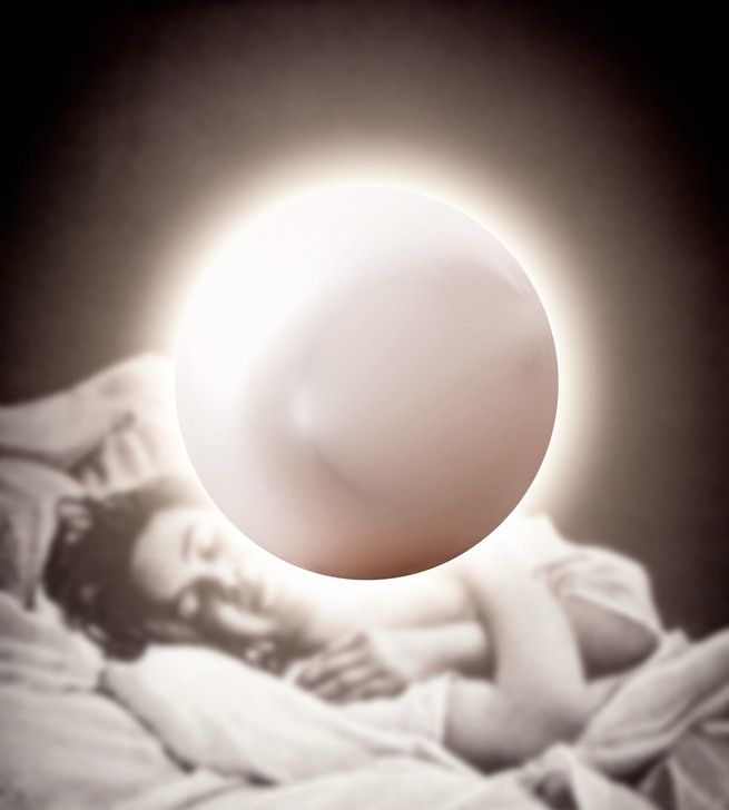 A person lying in a hospital bed with a glowing orb in front of them