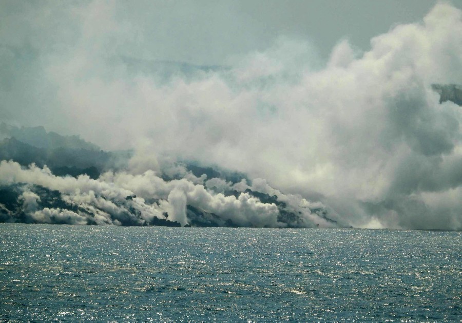 Steam rises as lava flows into the ocean.