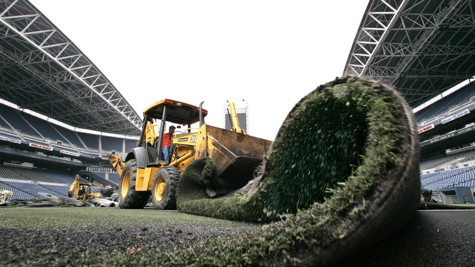 A truck removes artificial turf from a football stadium.