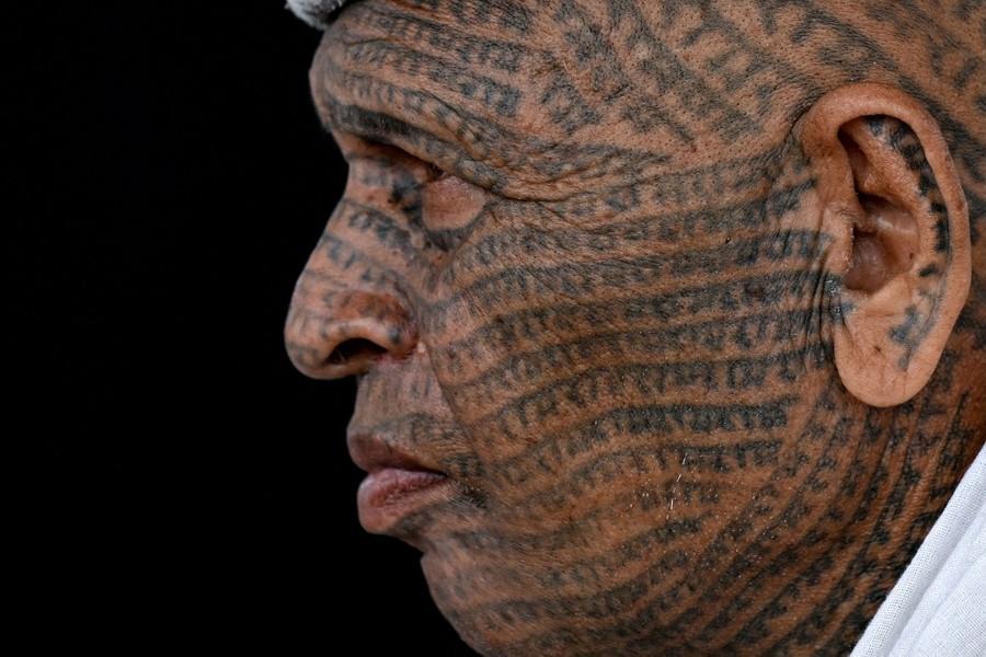 A man with many lines of text tattooed across his face